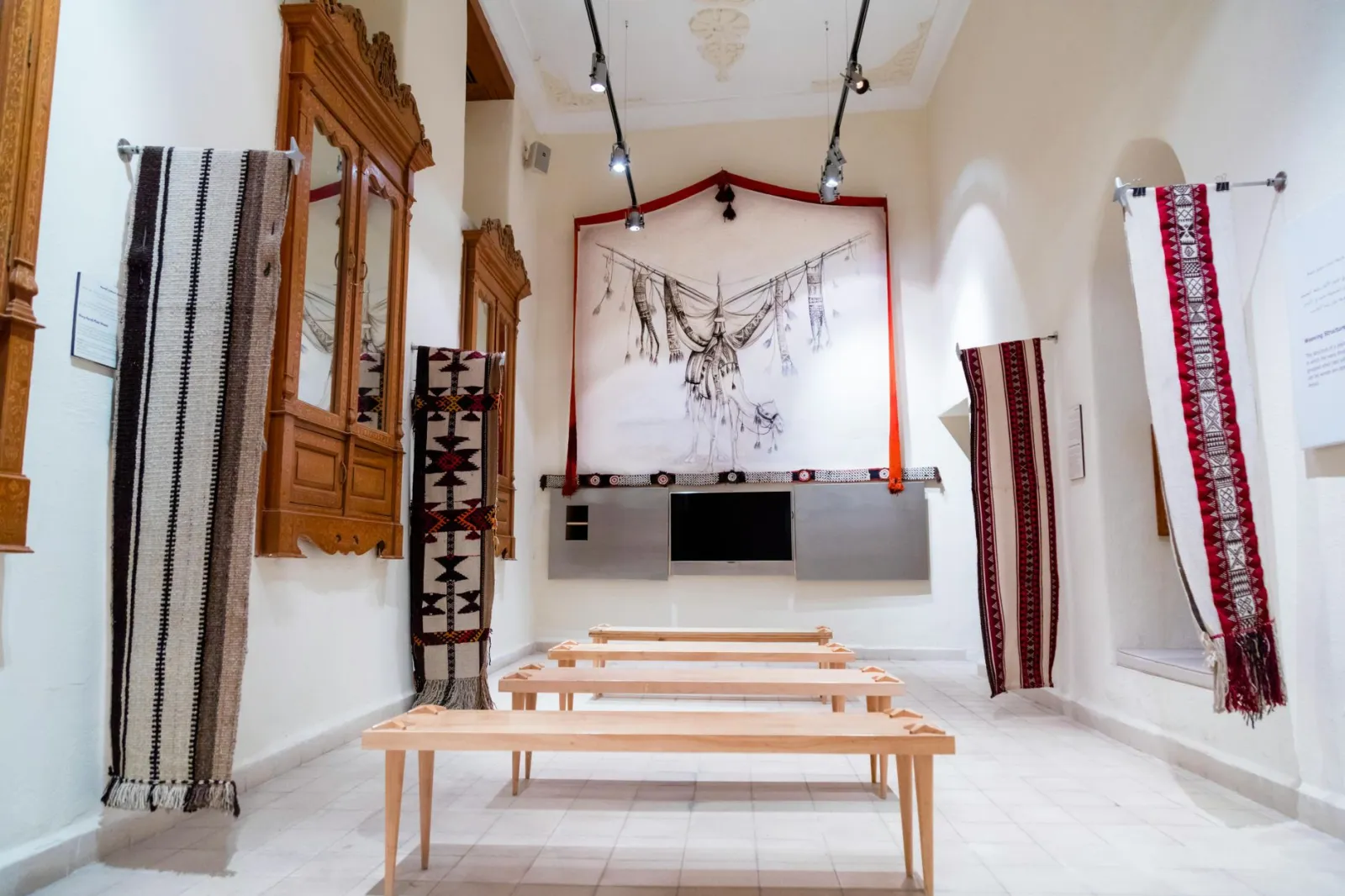 Exhibit room showcasing traditional woven textiles on display in a bright museum setting.