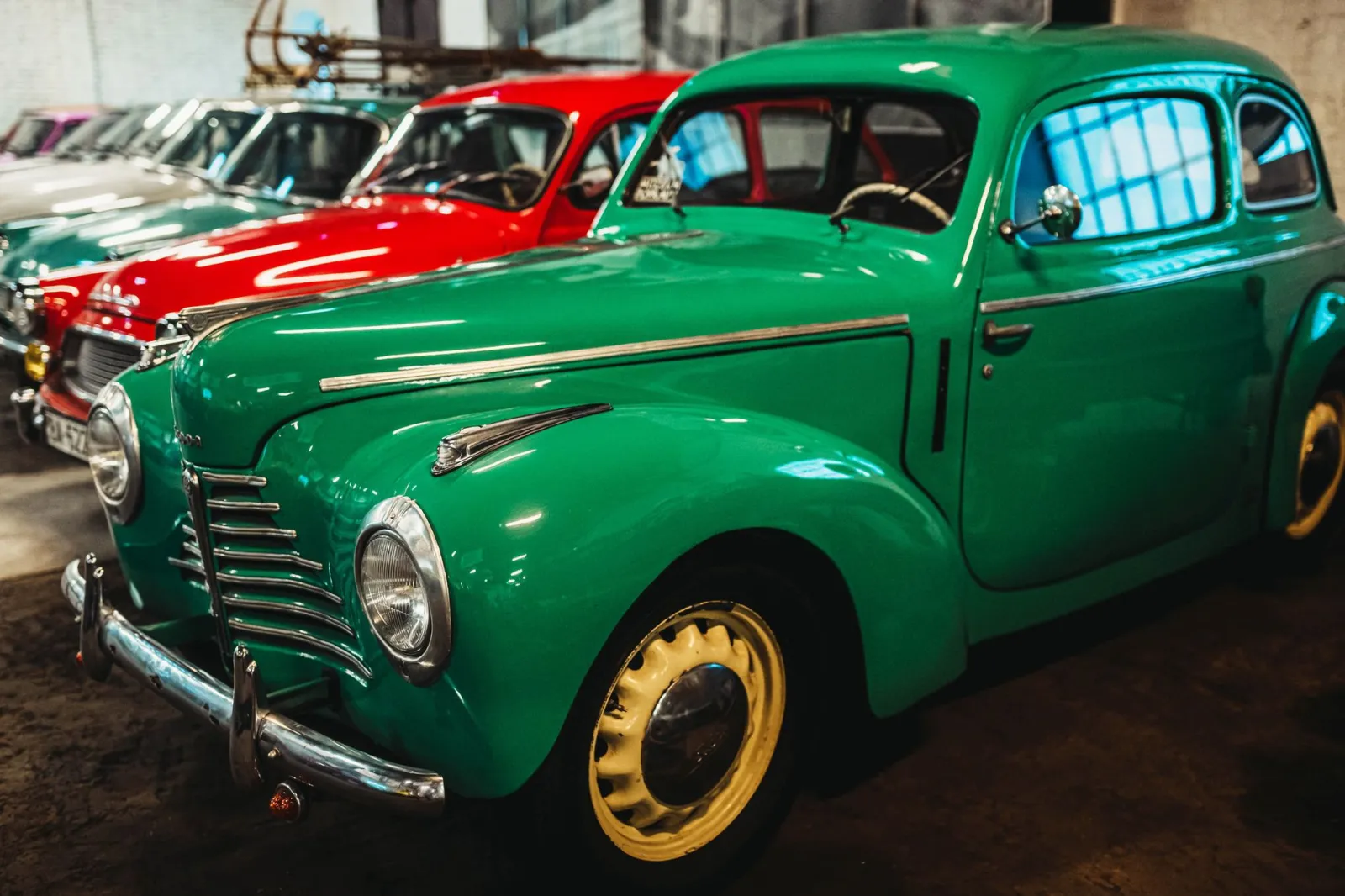 Ilustracyjna oś czasu historii motoryzacji z sylwetkami samochodów różnych epok na tle zarysu Polski