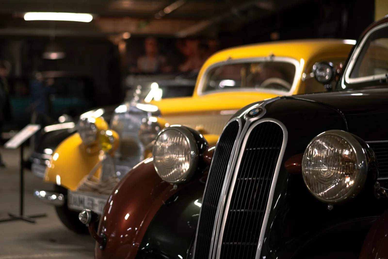 Wnętrze muzeum motoryzacji z zabytkowymi samochodami na wystawie i zwiedzającymi