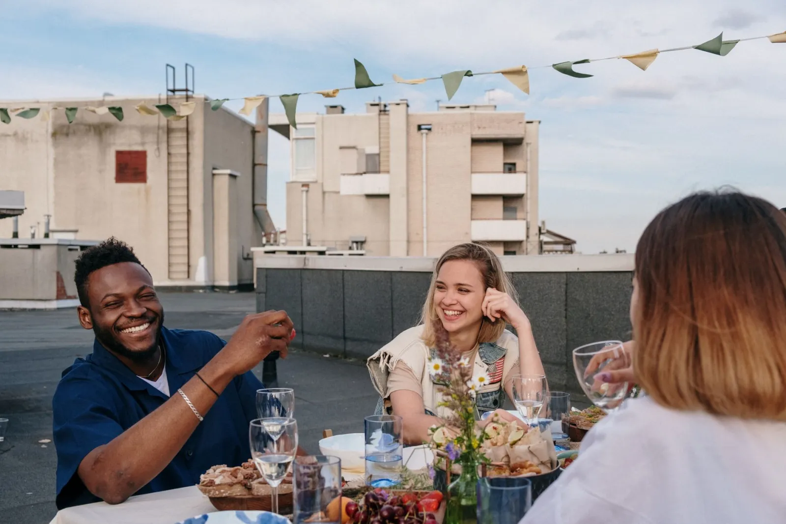 Group of friends enjoying a relaxed rooftop meal with laughter and good vibes.
